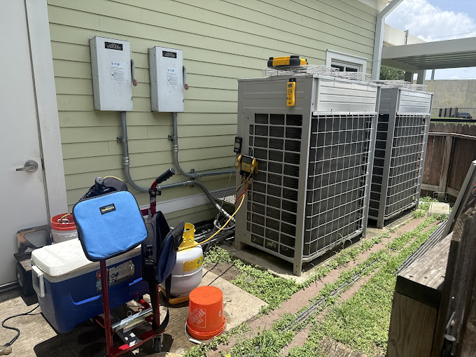 Two newly installed air conditioning condenser units with electrical disconnects and Texas Heatwave install tools during an AC replacement in the Rio Grande Valley