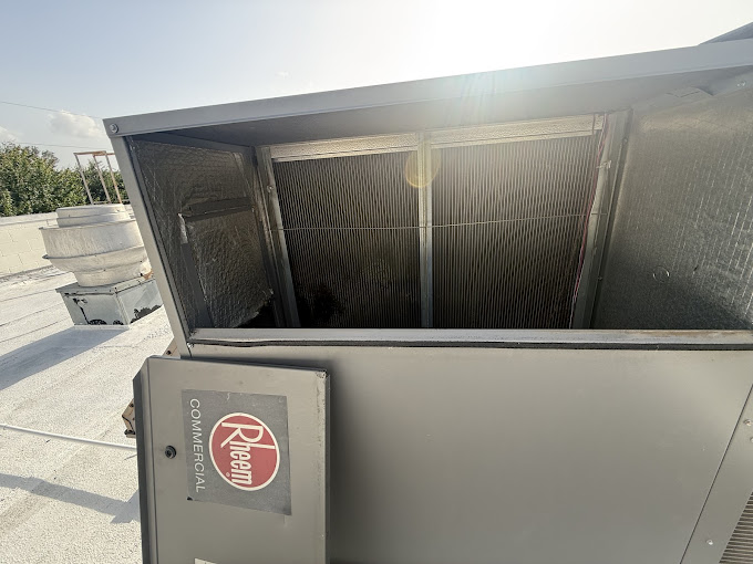 Texas Heatwave technician working on an opened commercial rooftop HVAC unit during an urgent service call