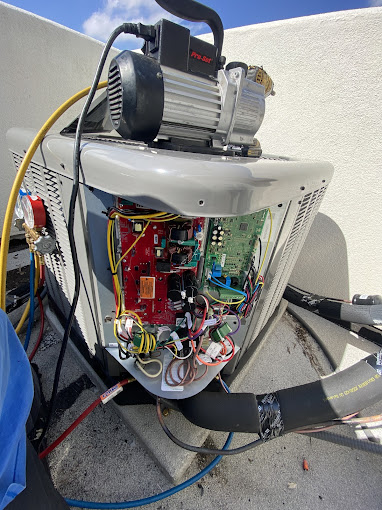 Open air conditioner control board and wiring being repaired by a Texas Heatwave technician on an outdoor unit