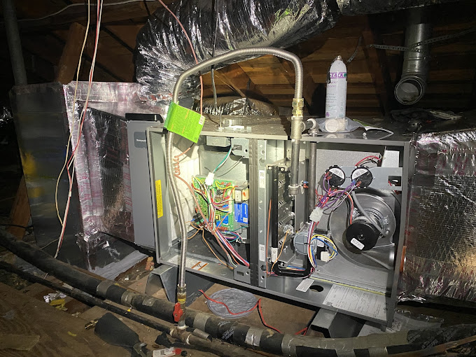 Texas Heatwave technician inspecting an open air handler — blower, control board, and wiring — during an HVAC maintenance visit