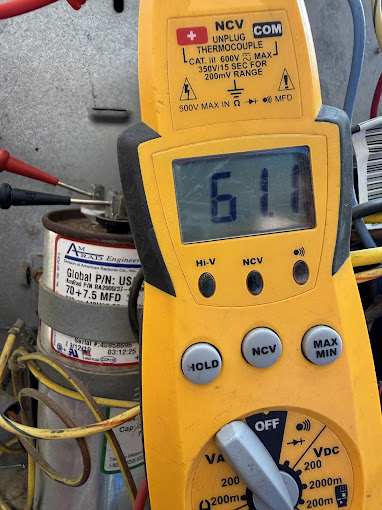 Texas Heatwave technician testing an AC capacitor with a digital multimeter to diagnose a system that won't cool