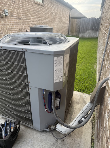 Residential air conditioning condenser with a Texas Heatwave technician's gauge bag beside it during an AC repair visit in the Rio Grande Valley
