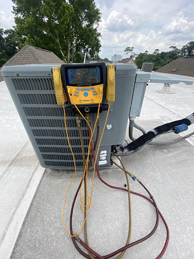 Texas Heatwave technician checking refrigerant pressures on a rooftop AC unit during a seasonal tune-up